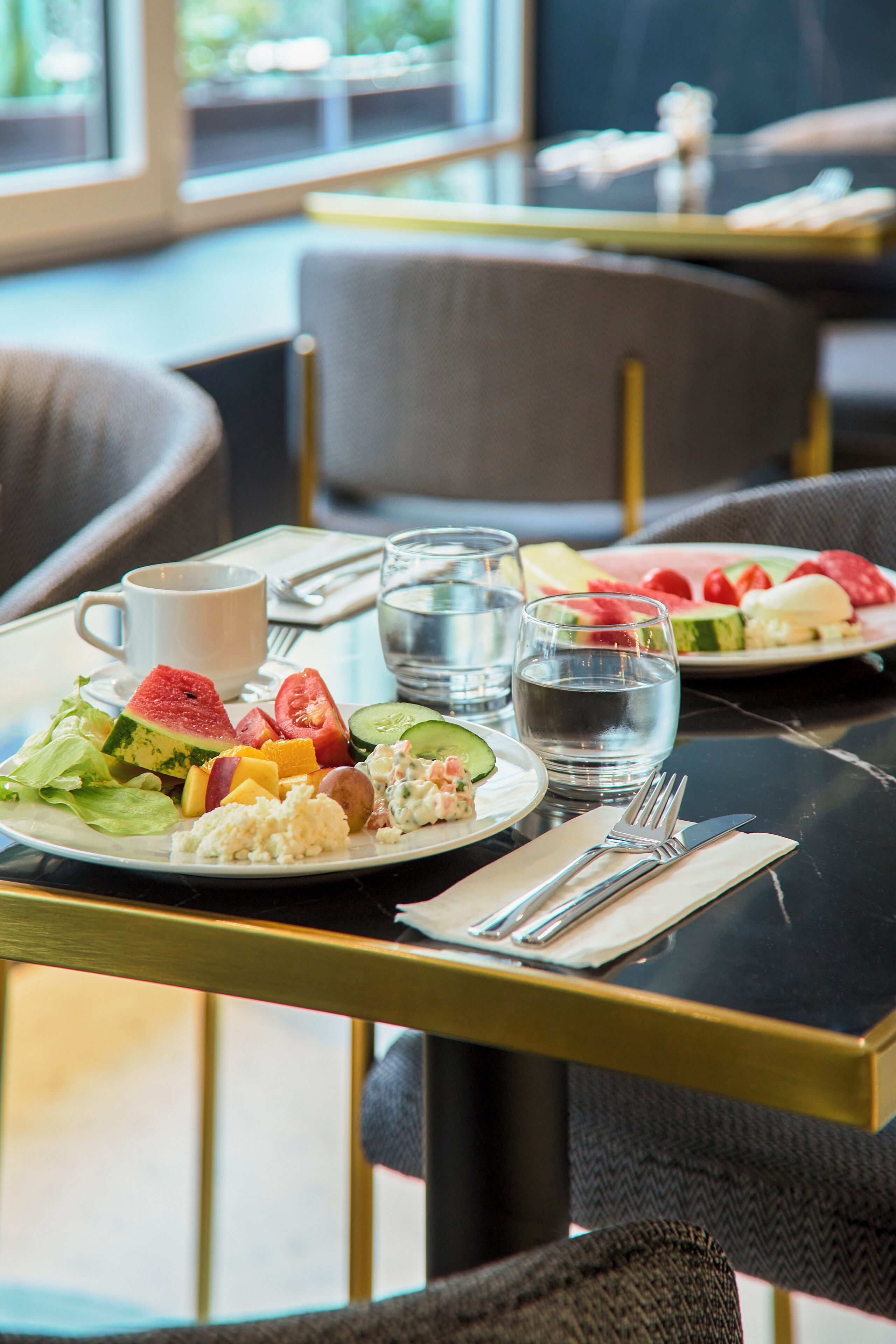 Une table à manger avec une assiette de nourriture, une tasse et des verres d’eau.