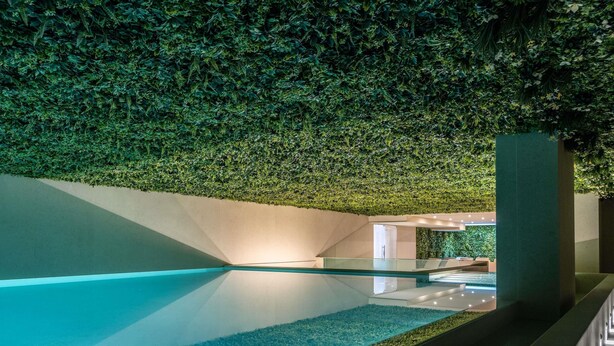 A modern indoor pool with a glass bottom, surrounded by walls covered in green foliage. - Novotel Malta Sliema (Gzira)