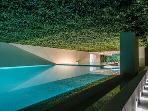 A modern indoor pool with a glass bottom, surrounded by walls covered in green foliage. - Novotel Malta Sliema (Gzira)