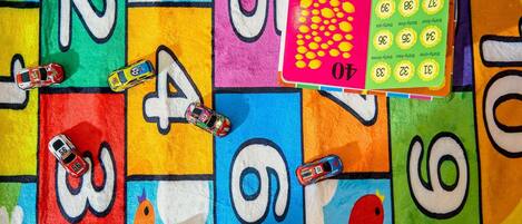 A colorful educational mat with numbers and cars, a puzzle, and a bird illustration.