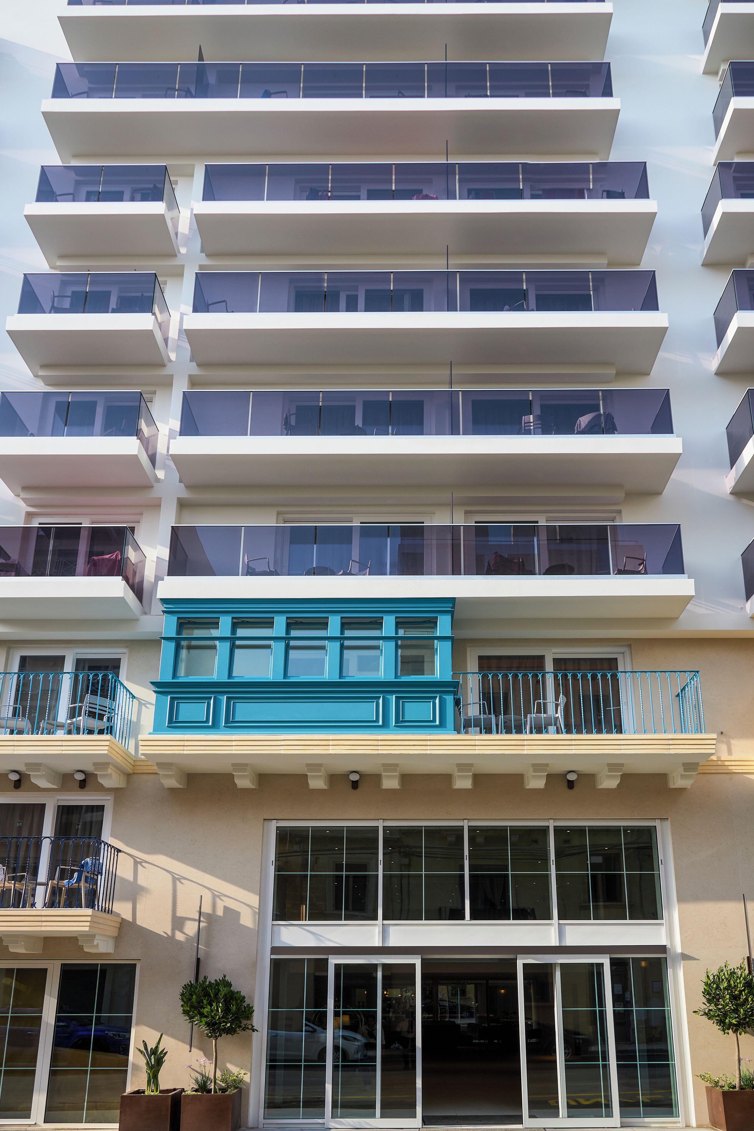 A multi-story hotel with balconies, large windows, and a blue accent on the facade.