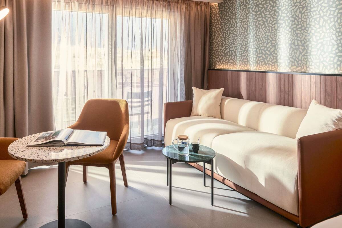 A modern hotel room with a sofa, a round table, and a chair.