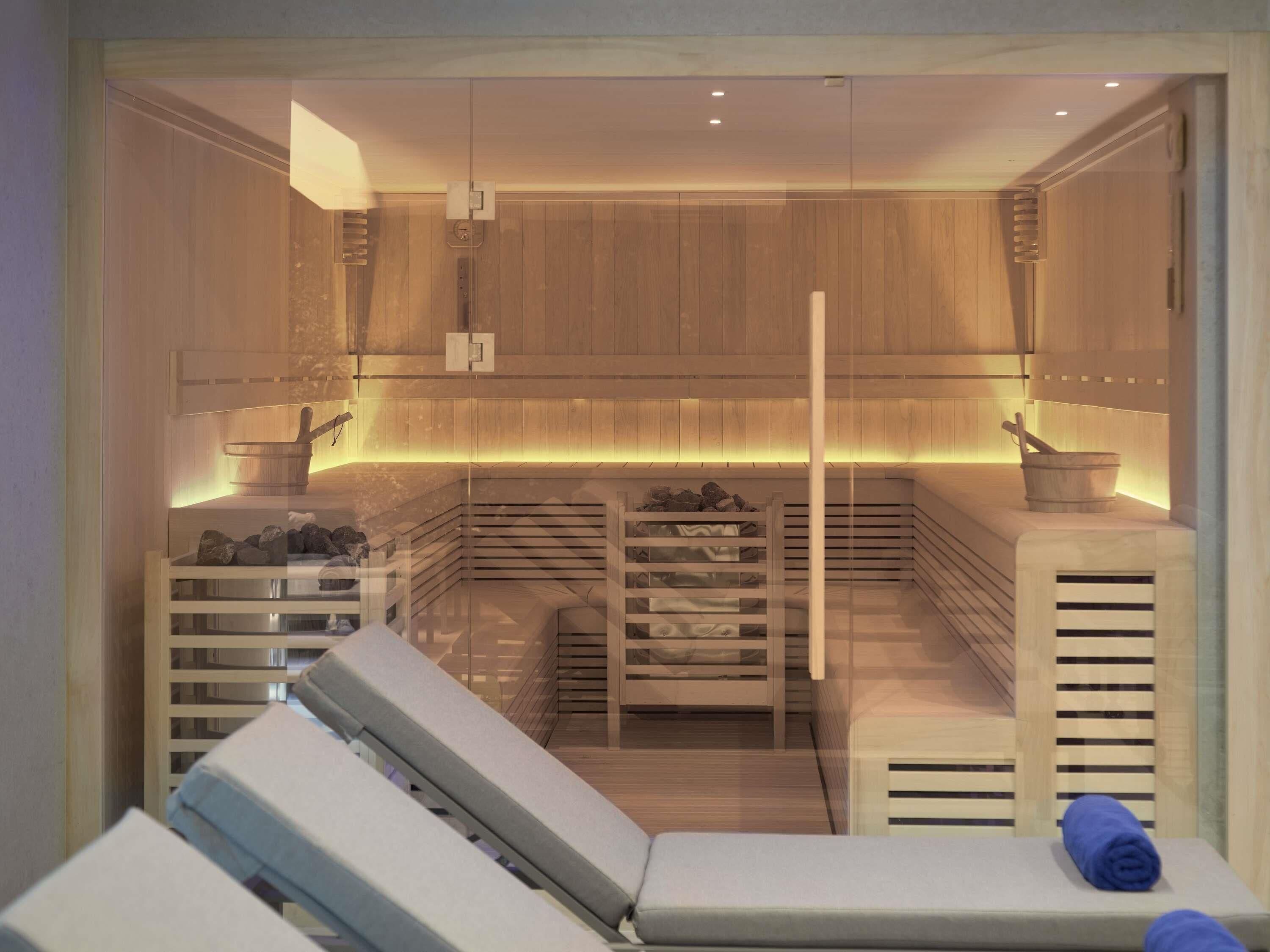 A sauna room with wooden walls, a bench, a massage table, and a towel.
