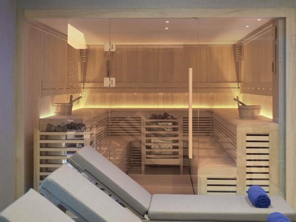Un cuarto de sauna con paredes de madera, un banco, una mesa de masajes y una toalla.