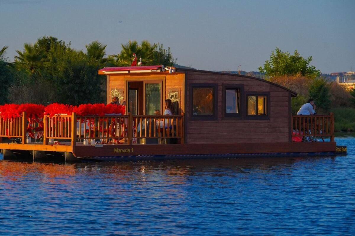 A wooden houseboat with a deck area, a covered section, and a name "Marvida 1".