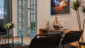 Un saló modern amb una porta blava, una taula de cafè de vidre, un sofà negre i una obra d'art emmarcada a la paret.