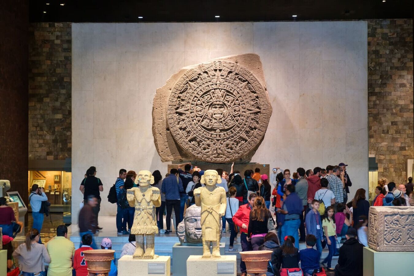Interior de museo con una gran talla de piedra y varias estatuas expuestas.