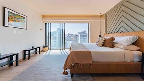 A modern bedroom with a large bed, a city view, and a minimalist design.