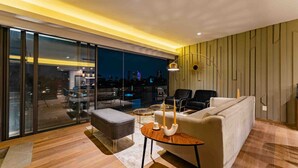 A modern living room with a sofa, two armchairs, a coffee table, and a glass door leading to an outdoor area.