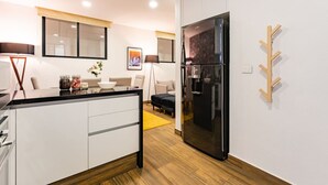 Une cuisine moderne dotée d’un grand réfrigérateur, de meubles blancs et d’un plancher en bois.