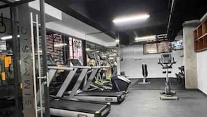 Une salle de sport équipée de tapis de course, d’appareils de musculation et d’un sac de frappe.