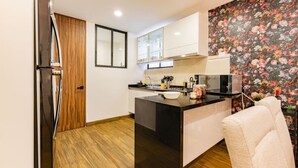 Une cuisine moderne avec un îlot central, un plancher en bois et un mur d’accent orné d’un papier peint à motifs floraux.