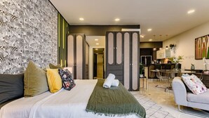 A modern hotel room with a large bed, a sofa, a dining area, and a kitchen. - Stylish Reforma Loft w/Pool, Gym, AC & City Views (Ciudad de México)