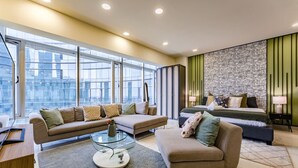 A modern living room with a sofa set, a glass coffee table, and a bed with a patterned headboard. - Stylish Reforma Loft w/Pool, Gym, AC & City Views (Ciudad de México)