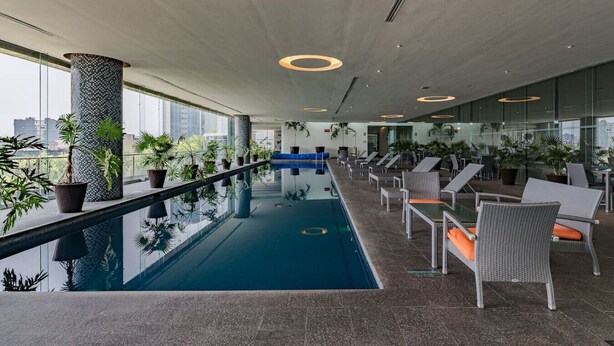 A modern indoor pool area with lounge chairs and potted plants. - Stylish Reforma Loft w/Pool, Gym, AC & City Views (Ciudad de México)