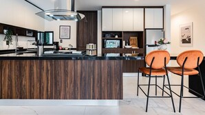 Une cuisine moderne avec un îlot central, des tabourets de bar et une grande fenêtre.