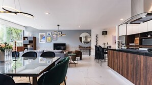 Una cocina moderna con comedor, que cuenta con una isla grande, armarios de madera oscura y un espejo amplio.