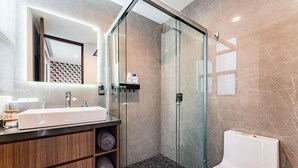 A modern bathroom with a glass-enclosed shower, a white sink, and a toilet.