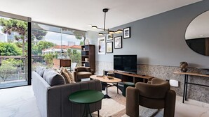 A modern living room with a sofa, armchairs, a coffee table, a TV, and a bookshelf.