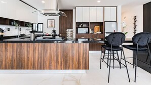 Una cocina moderna con una isla central, taburetes negros y un horno empotrado.