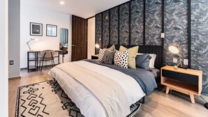Un dormitorio moderno con una cama grande, un escritorio y una mesita de noche.