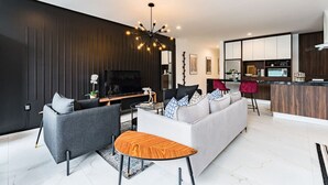 A modern living room with a sofa, chairs, a TV, and a kitchen area with cabinets and a countertop. - Stylish Polanco Duo Steps from Lincoln Park (Ciudad de México)