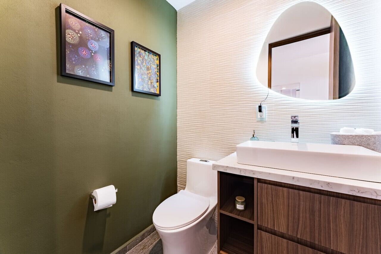 A bathroom with a toilet, a sink with a mirror, and two framed pictures on the wall.
