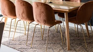 Un comedor moderno con una mesa grande, seis sillas de terciopelo, un jarrón con flores y un cuadro abstracto de gran tamaño en la pared.