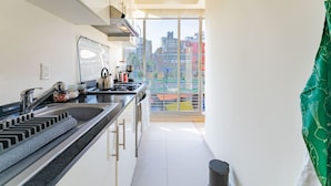 Una cucina moderna con un'ampia finestra, vista sulla città e un asciugamano verde appeso alla porta.