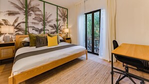 Un dormitorio con cama, mesitas de noche, un escritorio y un balcón con cortinas.