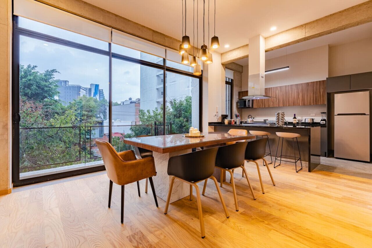 Cozinha moderna com uma ilha grande, banquetas de bar e vista para o verde lá fora.