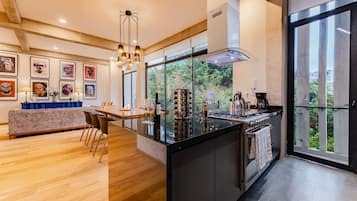 Uma cozinha moderna com uma ilha central, janelas amplas e um espaço de refeições com sofá e cadeiras.