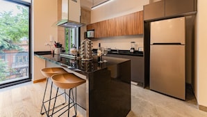 A modern kitchen with a large island, bar stools, a built-in oven, and a refrigerator.