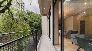 A modern apartment with a balcony, large windows, and a living area with a sofa and table.