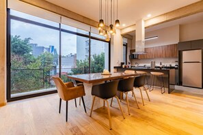 Une cuisine moderne dotée d’un grand îlot central, de tabourets de bar et offrant une vue sur la verdure environnante.