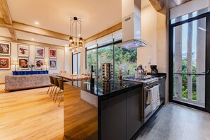 A modern kitchen with a central island, large windows, and a dining area with a sofa and chairs. - Group-Friendly Stay in Walkable Roma Norte (Ciudad de México)