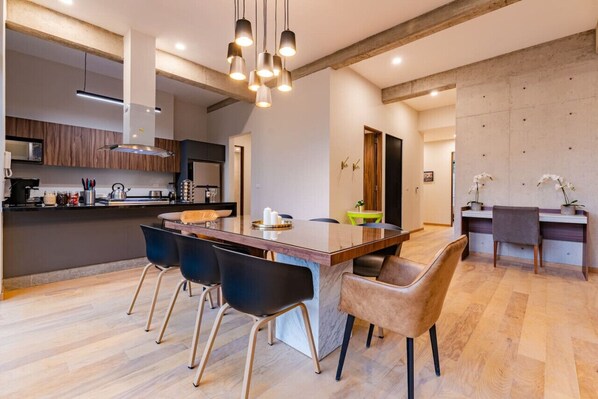 A modern kitchen with a central island, black chairs, and a dining area with a table and chairs.