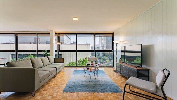 A modern living room with a sofa, a coffee table, a TV, and a chair.
