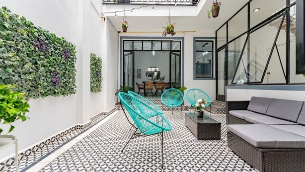 A modern patio with patterned flooring, a seating area with a sofa and chairs, and a balcony with plants. - Chillout Roma Vibes, Ping Pong, Walk to Top Bars (Ciudad de México)