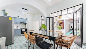 A modern kitchen with white cabinets, a dining area with a glass table and wicker chairs, and a patterned floor. - Chillout Roma Vibes, Ping Pong, Walk to Top Bars (Ciudad de México)
