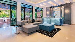 A modern living room with a sectional sofa, a small table, and a bar area with a counter. - Ideal for Groups, Rooftop, BBQ, Walk to Reforma (Ciudad de México)