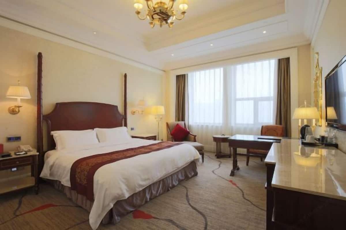 Een hotelkamer met een groot bed, nachtkastjes, een bureau en een stoel.