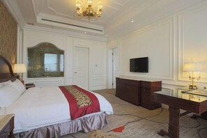 A hotel room with a large bed, a wooden dresser, a desk with a lamp, a flat-screen TV, and a chandelier. - Liaobin Paxton Vacances Hotel Panjin (Panjin)