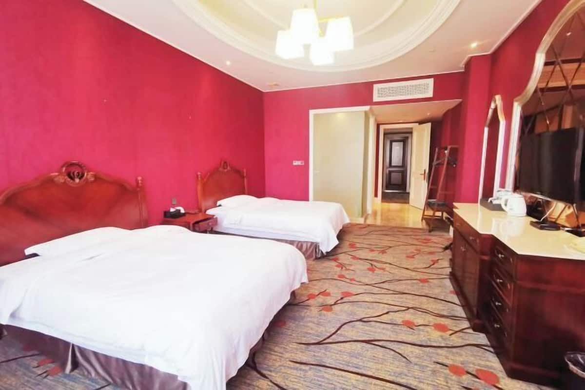 Een hotelkamer met twee bedden, een dressoir, een spiegel en een televisie.