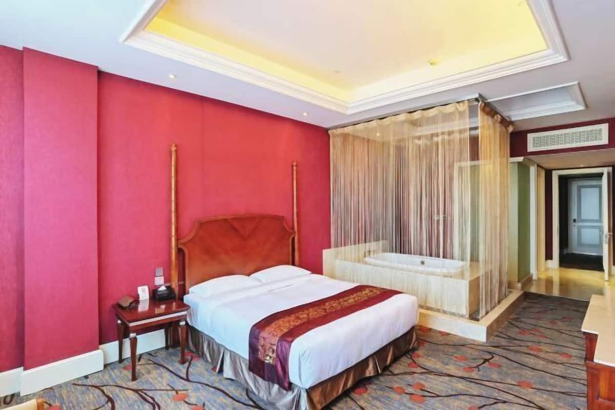 Een hotelkamer met een bed, nachtkastje en hemelbed.
