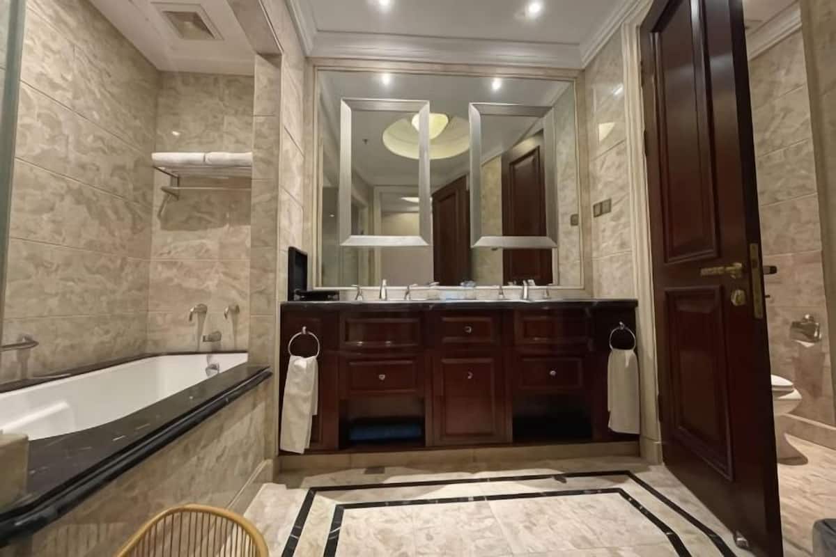 Een badkamer met een bad, een wastafel met twee kommen en een spiegel, en een toilet.