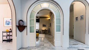 Un couloir doté d’un sol en marbre, de murs blancs et d’une étagère en bois ornée d’objets décoratifs.
