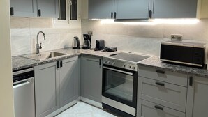 A modern kitchen with grey cabinets, a stainless steel sink, a built-in oven, and a microwave.