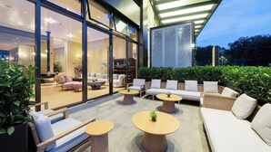 An outdoor seating area with sofas, round tables, and potted plants. - Mercure Guangzhou Baiyun International Airport (Guangzhou)