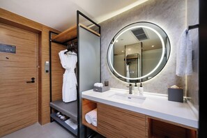 A modern bathroom with a wooden vanity, a round mirror with a light, and a built-in shower. - Mercure Guangzhou Baiyun International Airport (Guangzhou)